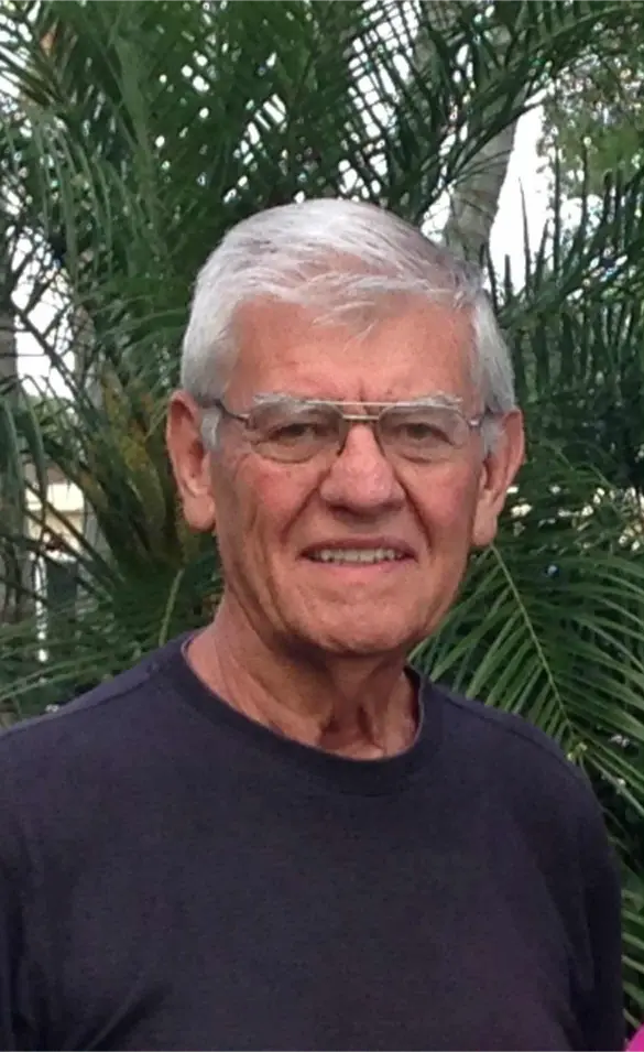 Roger Brewer smiling man with dark blue shirt and a fern tree behind him