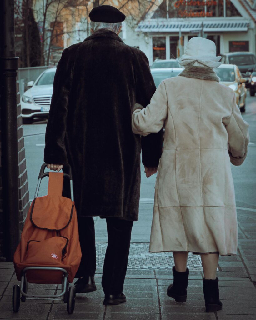 elderly couple walking down street in coats