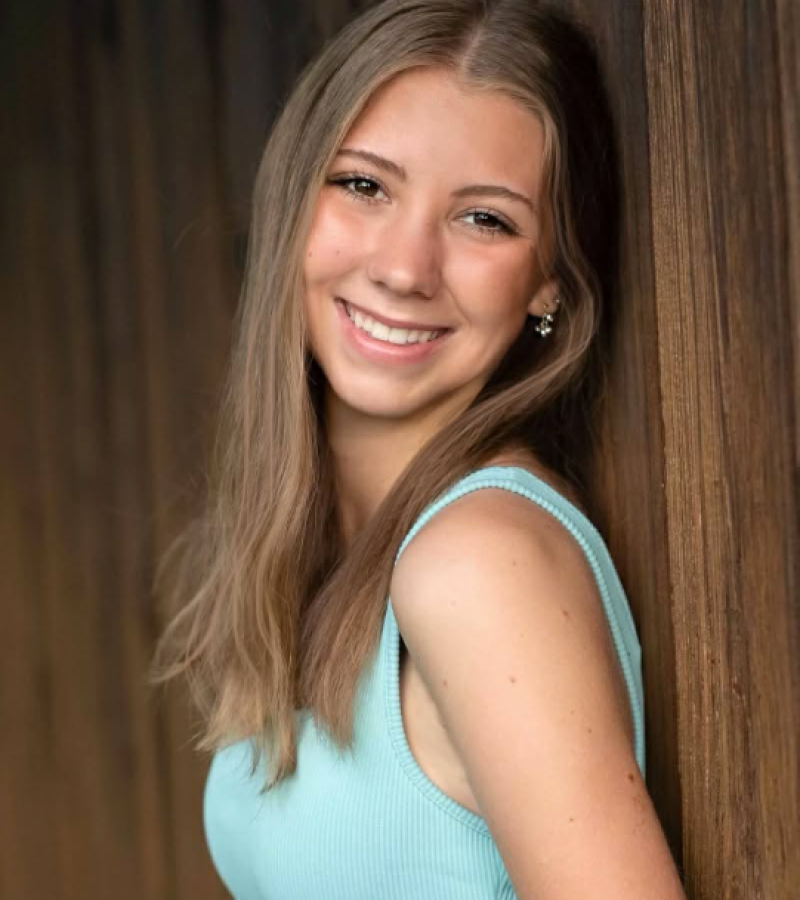 Keira Krenz light blue tank top smiling at the camera young female long sandy blond hair.